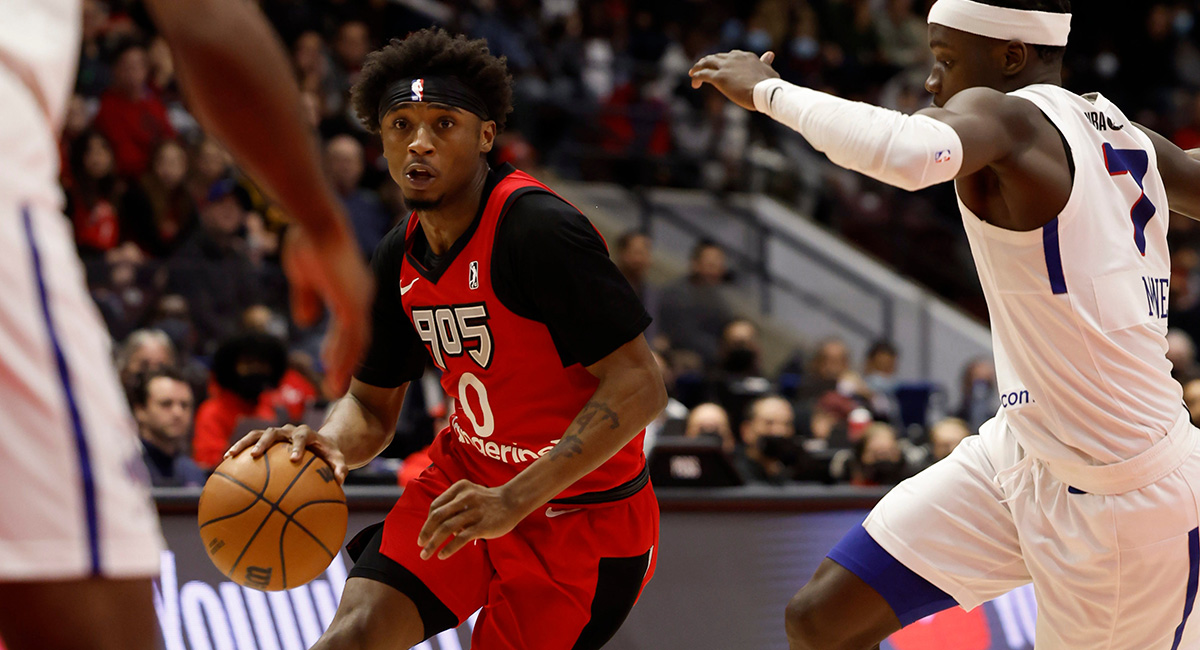 A Raptors 905 player dribbling a ball between two opposing players.