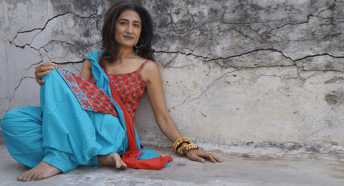 Kiran Ahluwalia sitting against a wall.