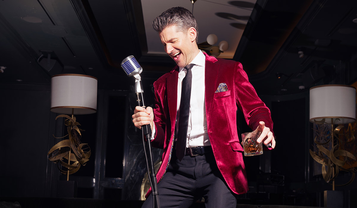 Matt Dusk holding a microphone in a dark room