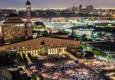 City Hall lit up at night, with hundreds of people in Celebration Square