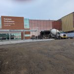 Construction ongoing at the Carmen Corbasson Community Centre main entrance with a cement truck and workers present.