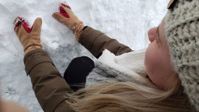 A lady with gathering snow in her hands.