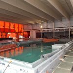 An inside pool full of water with orange tarps covering the far wall.
