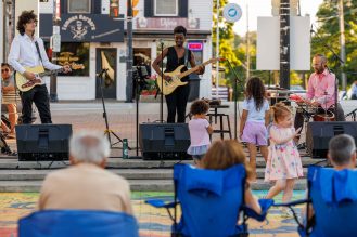 Singers playing instruments outdoors at the open Summer Concert Series