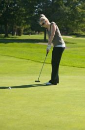 A woman playing golf in the sunshine