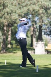 A woman playing golf surrounded by a big tree