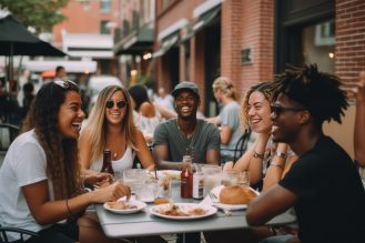 Group of friends laughing while enjoying a meal at an outdoor restaurant patio