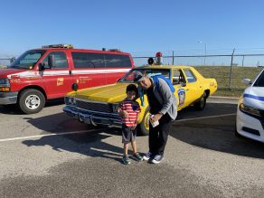 Child and parent with an older police car at the event