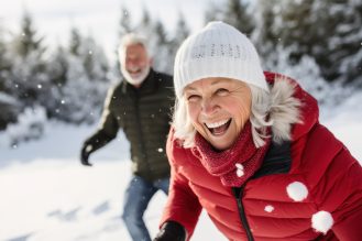 Close-up of woman smiling on a snowy day with a man smiling in the background