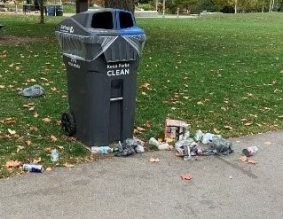 City's waste and recycling bin with litter scattered on ground.