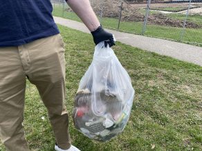 Person holding bag of litter from a litter clean-up at a park.