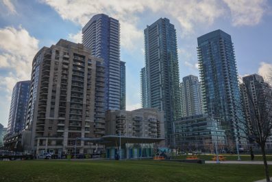 A group of tall building with a large green space in front