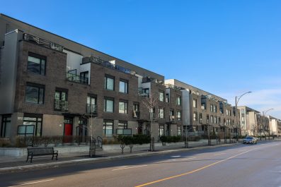 A row of modern brick townhouses beside two-way road