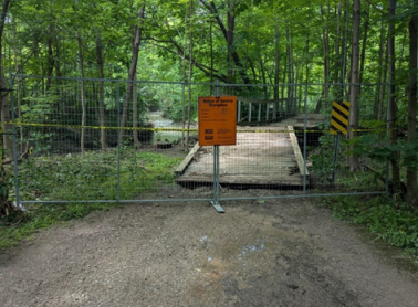 Barricades and signage along a flooded City trail