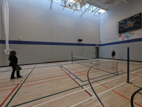 Two people playing pickleball on an indoor at a City community centre