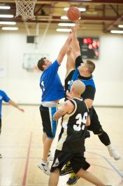 Men jump for a tip off during a basketball game.