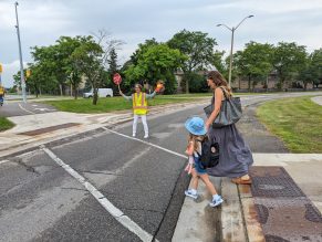 Student and parent crossing road with crossing guard.