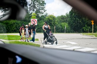 Students and parent walking across road from a driver's point of view.