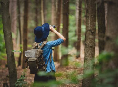 Young woman with binocular and backpack in a forest