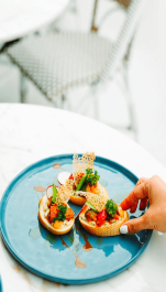 Someone reaching for a beautifully plated appetiser.