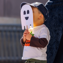 A child holding a pumpkin decoration in front of their face.