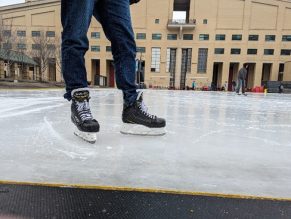 A man standing in ice skates on the rink at Celebration Square in Mississauga.