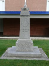 A multi-level granite monument with a stone flame in a bowl on top and a carved emblem of the Army, Navy & Air Force Veterans of Canada. The cenotaph is engraved with "World War II 1939~1945", and the inscriptions read "Dedicated 1971" and "By the grace of almighty God may all who pass this way hold sacred in their hearts the memories of those gallant comrades who have paid the supreme sacrifice"