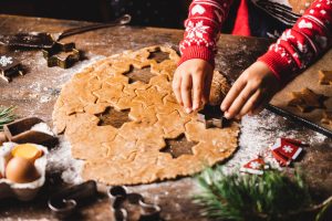 Boy's hand cutting dough with christmas star cookie cutter