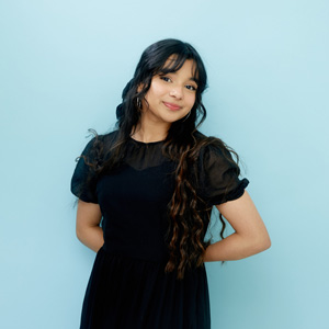 EMA posing in front of a light blue background.