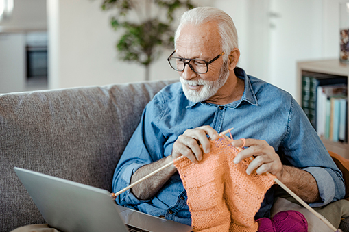 senior-man-doing-knit-work-watching-online-tutorial-at-home