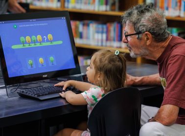 A middle aged man and toddler use a computer keyboard.