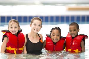 Swim instructor with kids in lifejackets