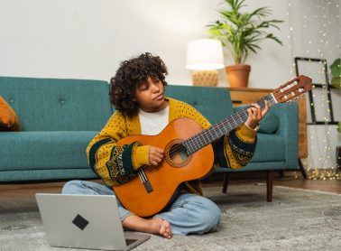 Woman playing guitar on the floor of her home